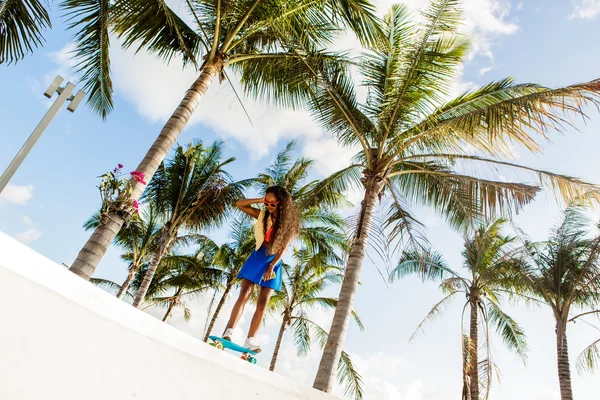 Beautiful teenage black girl in bright outfit rides at tropical — Stock Photo, Image