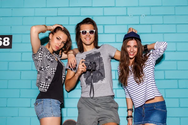 Happy young people with photo camera having fun in front of blue — Stock Photo, Image