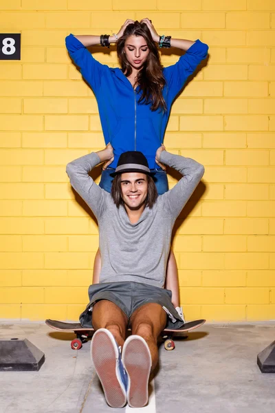 Felice giovane coppia divertirsi davanti al muro di mattoni gialli — Foto Stock