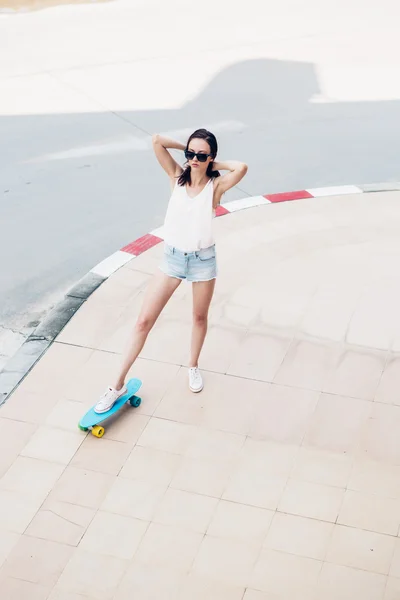 Meisje van de hipster met een skateboard op de straat. — Stockfoto