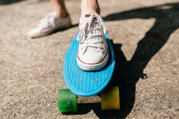 Ung flicka i sneakers på skateboard. — Stockfoto