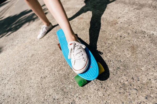 Ung flicka i sneakers på skateboard. — Stockfoto