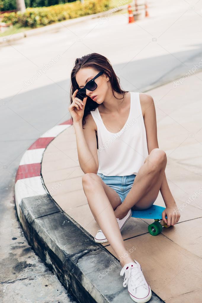 Hipster girl with skateboard on the street. Stock Photo by