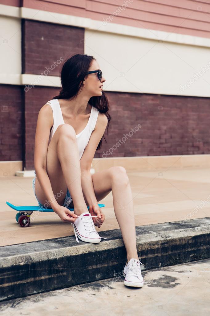 Hipster girl with skateboard on the street. Stock Photo by