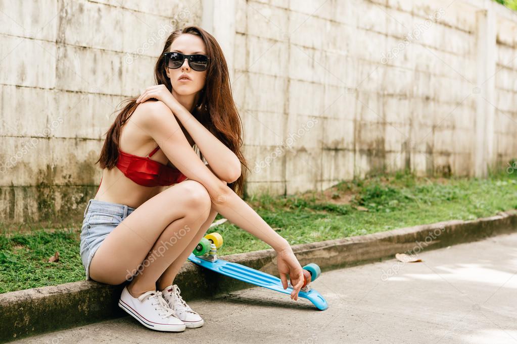 An attractive hipster girl in casual clothes sitting on an urban