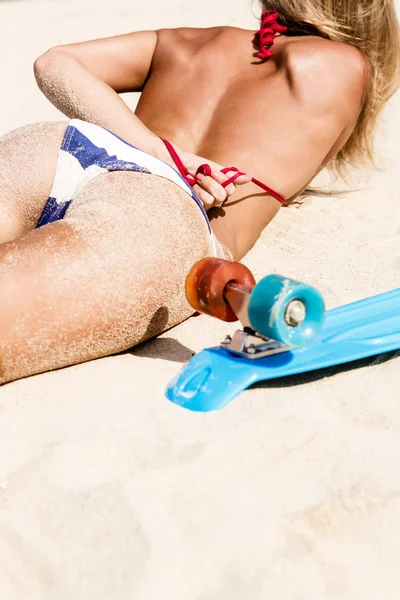 Сексуальная загорелая леди с голубой доской из пенни, лежащей на пляже — стоковое фото
