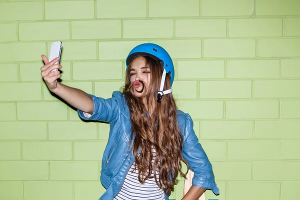 Bela mulher de cabelos longos com um smartpnone perto de um tijolo verde — Fotografia de Stock