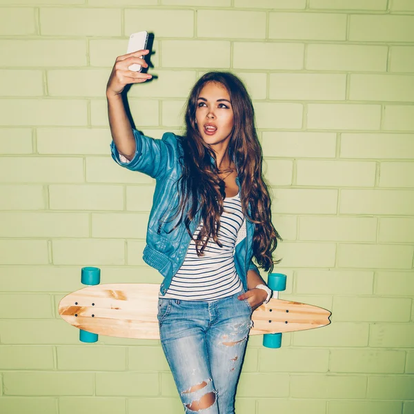 Woman with skateboard taking selfie — Zdjęcie stockowe