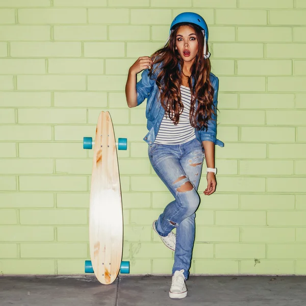 Belle femme aux cheveux longs avec un longboard en bois près d'un vert — Photo