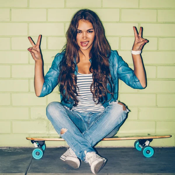 Vackra långhåriga kvinna med en trä skateboard nära en gree — Stockfoto