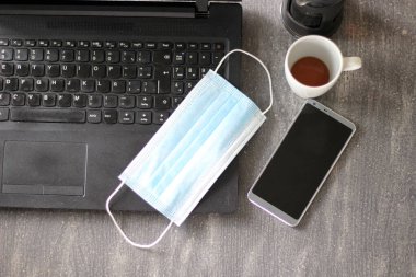 Kafe, cubrebocas y computadora preada para trabajo en casa
