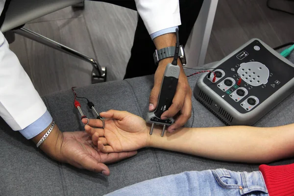 Doktorun elleri genç bir kadında elektromiyografi çalışması ve sinir iletimi yapıyor.