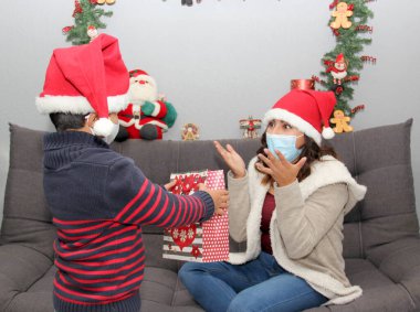 Latin anne ve çocuğu koruma maskesi ve Noel Baba şapkası, hediyeler ve Noel süslemeleri, yeni normal covid-19