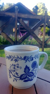 Sıcak çikolata, kulübe ve arka planda orman çitleri olan kupa manzarası