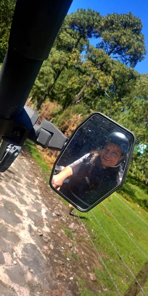Latin adult woman, view from a buggy car capable of driving on difficult terrain, such as dirt and mud, you can see the rear-view mirror and the road that leads to adventure