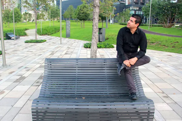 Casual Homem Latino Calças Cinza Camisa Preta Sentado Banco Parque — Fotografia de Stock