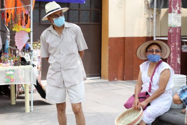 Koruyucu maskeli ve şapkalı yaşlı Latin çift meydanda yürüyor, yeni normal Cvid-19.