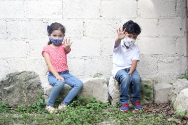 Arkasında beyaz bir duvar olan, siyah maske takan 6 yaşında Latin çocuklar, yeni normal insanlar.