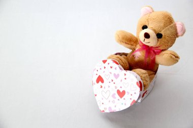 Oyuncak ayı, bir kutu çikolata ve beyaz arka planda kurdeleli pembe kalpler Sevgililer Günü hediyeleri, reklam afişi.