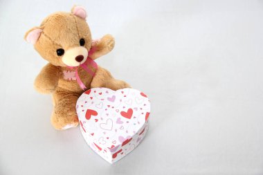 Oyuncak ayı, bir kutu çikolata ve beyaz arka planda kurdeleli pembe kalpler Sevgililer Günü hediyeleri, reklam afişi.