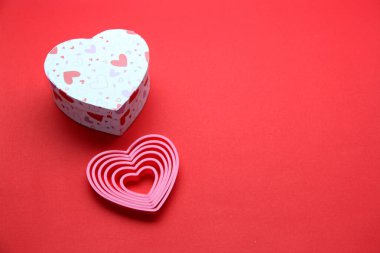 Oyuncak ayı, bir kutu çikolata ve kırmızı arka planda kurdeleli pembe kalpler Sevgililer Günü hediyeleri, reklam afişi.