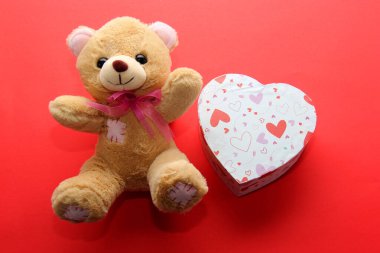 Sevgililer günü hediyeleri, çiçekler ve kırmızı arka planda kalpler olan çikolatalar.