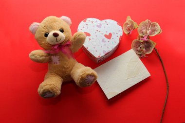 Sevgililer günü hediyeleri, çiçekler ve kırmızı arka planda kalpler olan çikolatalar.