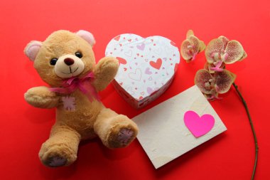 Sevgililer günü hediyeleri, çiçekler ve kırmızı arka planda kalpler olan çikolatalar.