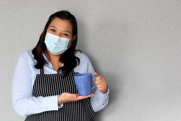 Latin chef woman with protection mask and coffee cups, new normality covid-19 in cafes and restaurants