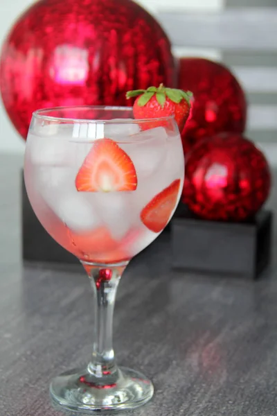 Strawberry gin and tonic on gray vintage table and red spheres