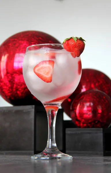 Strawberry gin and tonic on gray vintage table and red spheres