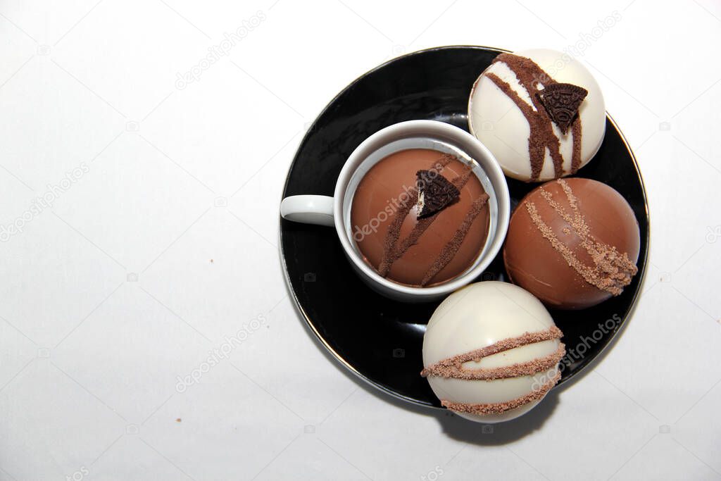 chocolate bombs in mug with hot milk, filled with marshmallows and white chocolate on white background