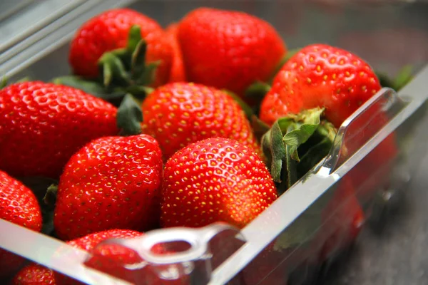 Plastik ambalajda meyve, kırmızı çilek. Klasik gri ahşap arkaplan