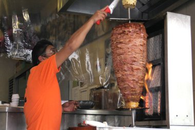 Latin Taquero adam koruma maskesiyle çalışıyor, tipik Meksika yemeği tacoları al pastor, yeni normal covid-19