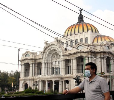 Mexico City 'de koruma maskeli Latin bir adam, arka planda Güzel Sanatlar Sarayı, yeni normal Cvid-19.