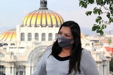 Meksika 'da koruma maskeli Latin bir kadın. Arka planda normal ve tarihi anıtlar var. Güzel sanatlar sarayı.