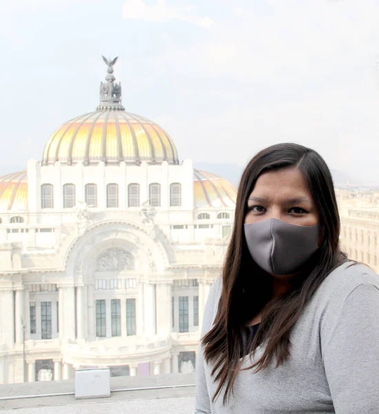 latin woman with protection mask in mexico city with the new normal and historical monuments in the background, palace of fine arts