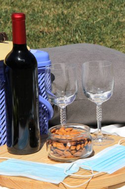 Piknik salgınında. Ormanda şarap ve yiyecek dolu sepet ve koruyucu maskeler.