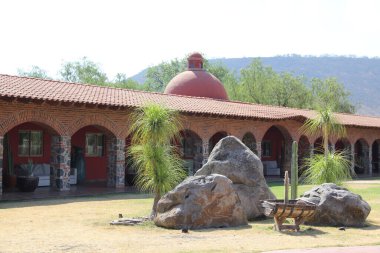 Koloni çiftliği ve kır evi, kemer ve yeşil çimen bahçeli taş ve kırmızı tuğla yapı