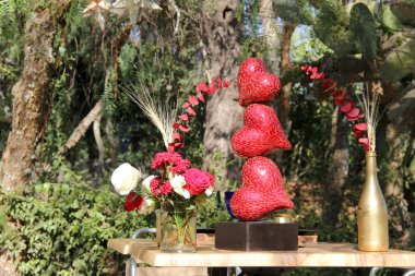 Orman bitkilerinde çiçekler ve kırmızı kalplerle romantik bir dekorasyon. Aşk günü.