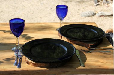 Sevgililer gününde yeşillik, çiçek ve kalp süslemeleriyle romantik yemek takımı ve mavi bardaklar.