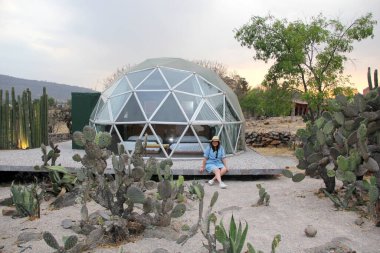 Jeodezik bir çadırın dışında gökyüzünü ve yıldızları görmek için saydam pencereleri olan Latin bir kadın.