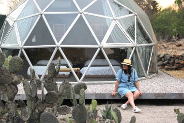 Jeodezik bir çadırın dışında gökyüzünü ve yıldızları görmek için saydam pencereleri olan Latin bir kadın.