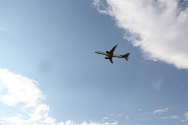 Bulutların arasında mavi gökyüzünde uçan uçak