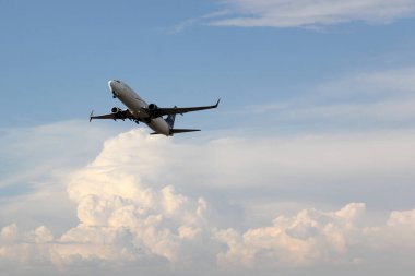 Bulutların arasında mavi gökyüzünde uçan uçak