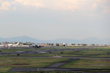 Uçak pistten kalkıyor, bulutların arasında uçuyor, yüksekliğini arttırıyor.