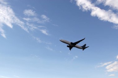 Bulutlar ve dağlar arasında mavi gökyüzü olan uçak kalkıyor ya da iniyor