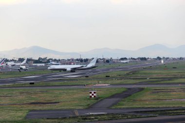Bulutlar ve dağlar arasında mavi gökyüzü olan uçak kalkıyor ya da iniyor