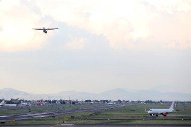 Mavi gökyüzü ile büyük bulutlar arasında uçak kalkıyor.