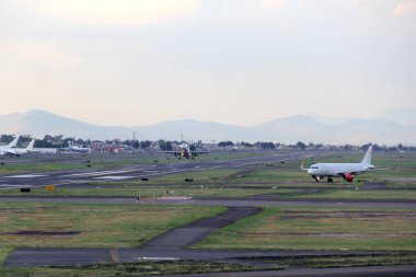 Mavi gökyüzü ile büyük bulutlar arasında uçak kalkıyor.